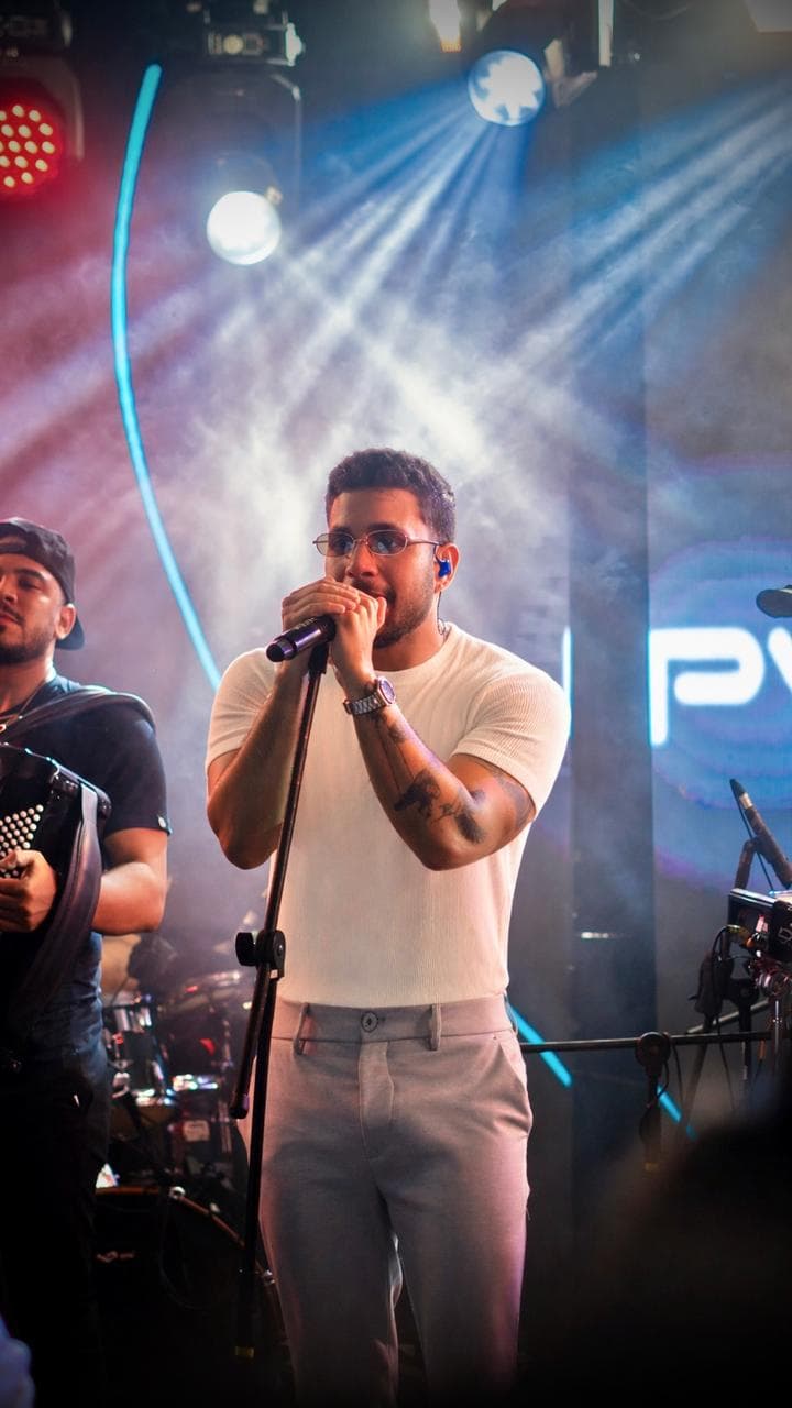 PV Mello cantando no palco entre feixes de luz e fumaça